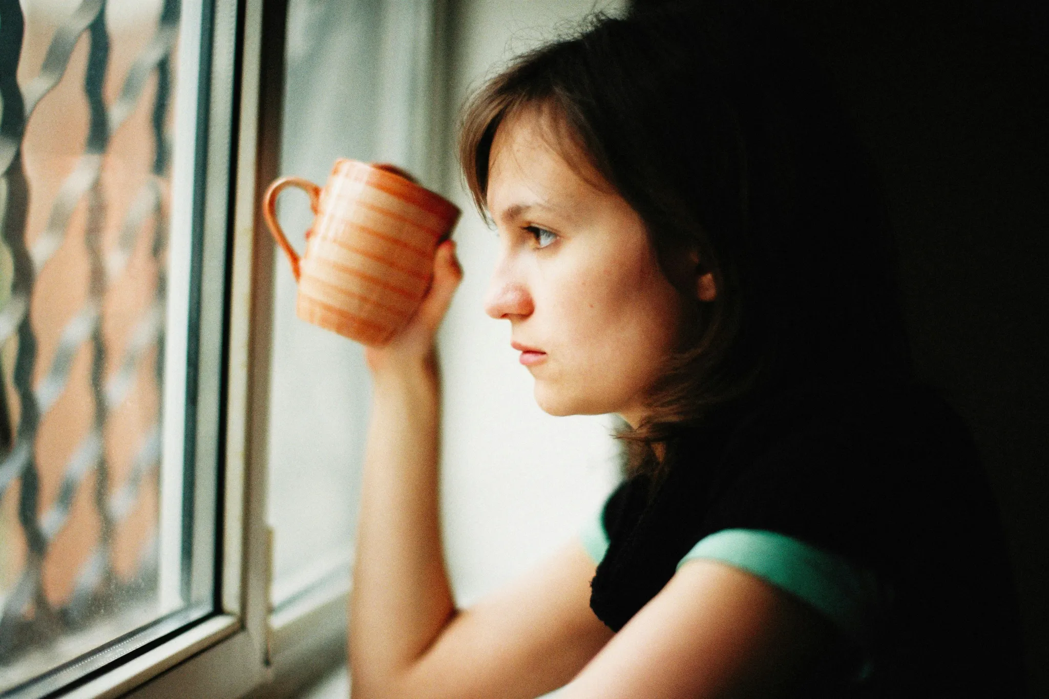 A woman holding a mug looking out of the window