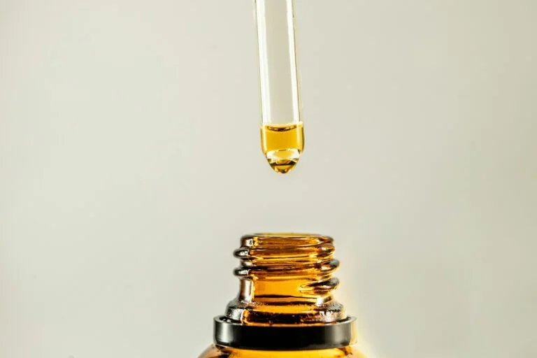 a dropper dispensing oil into a bottle