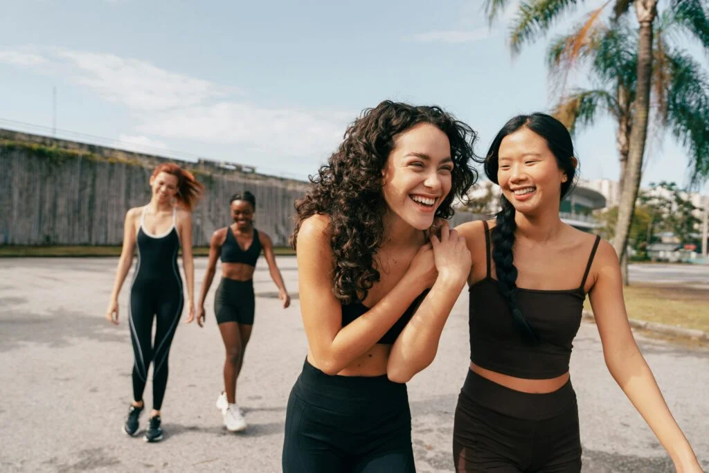 two women laughing whilst outdoors with friends