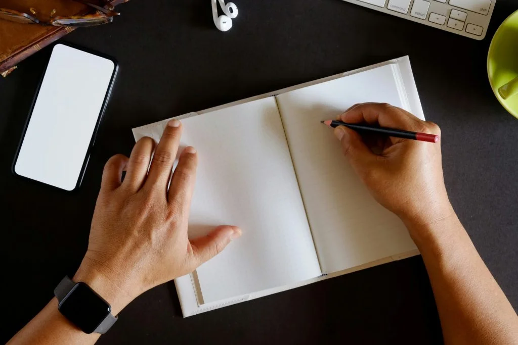 Person writing on notebook at home or office