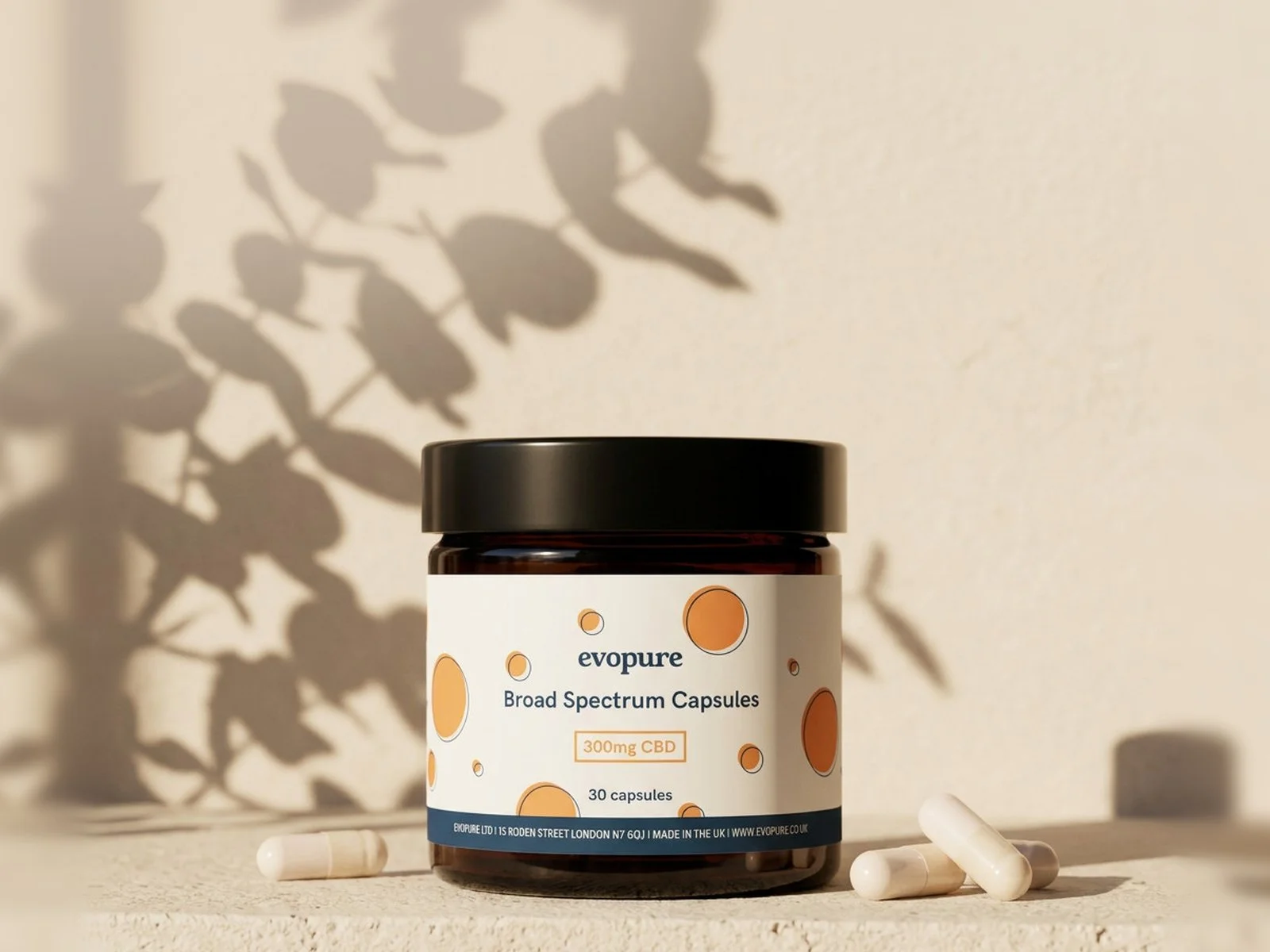Evopure Broad Spectrum CBD capsules jar on a sand-coloured ledge with leaf shadows