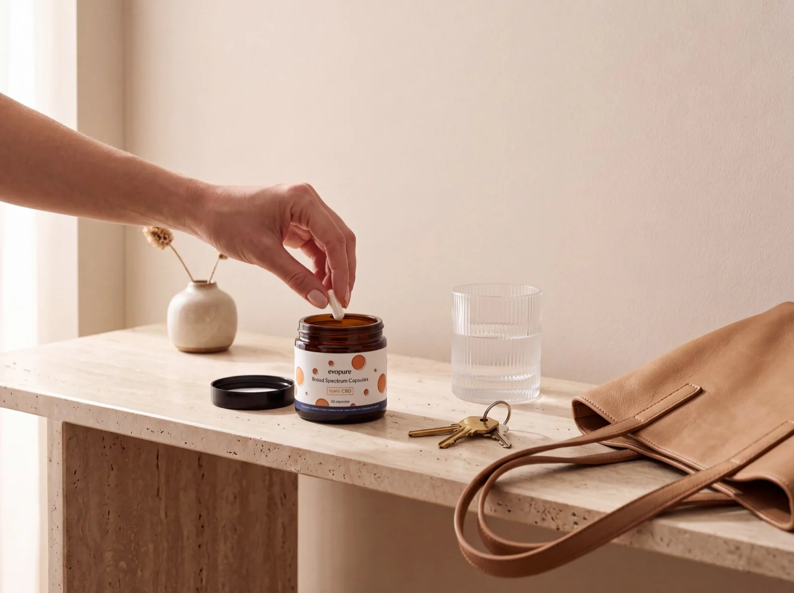 Evopure Broad Spectrum CBD capsules jar on a sand-coloured ledge with leaf shadows