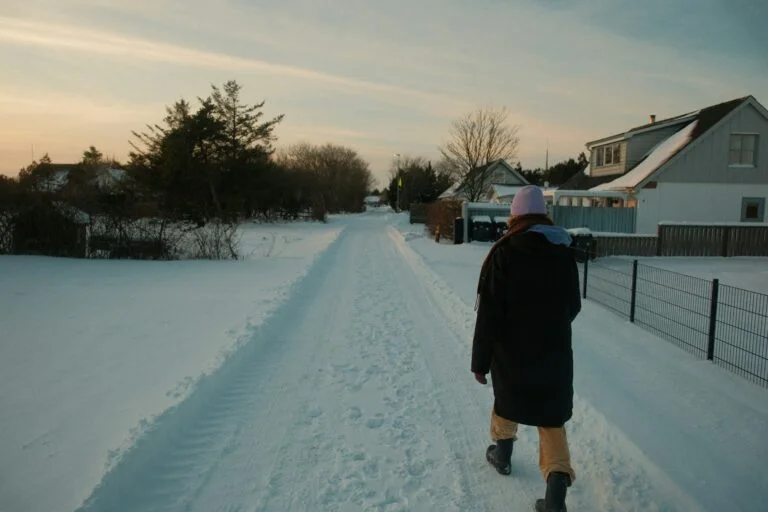 Person walking down a snowy path near houses