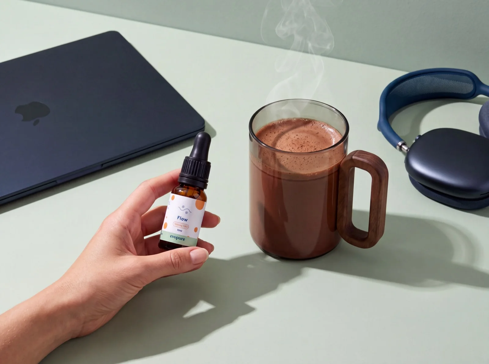 Evopure Flow CBD oil bottle and box on a sage wall with leaf shadows