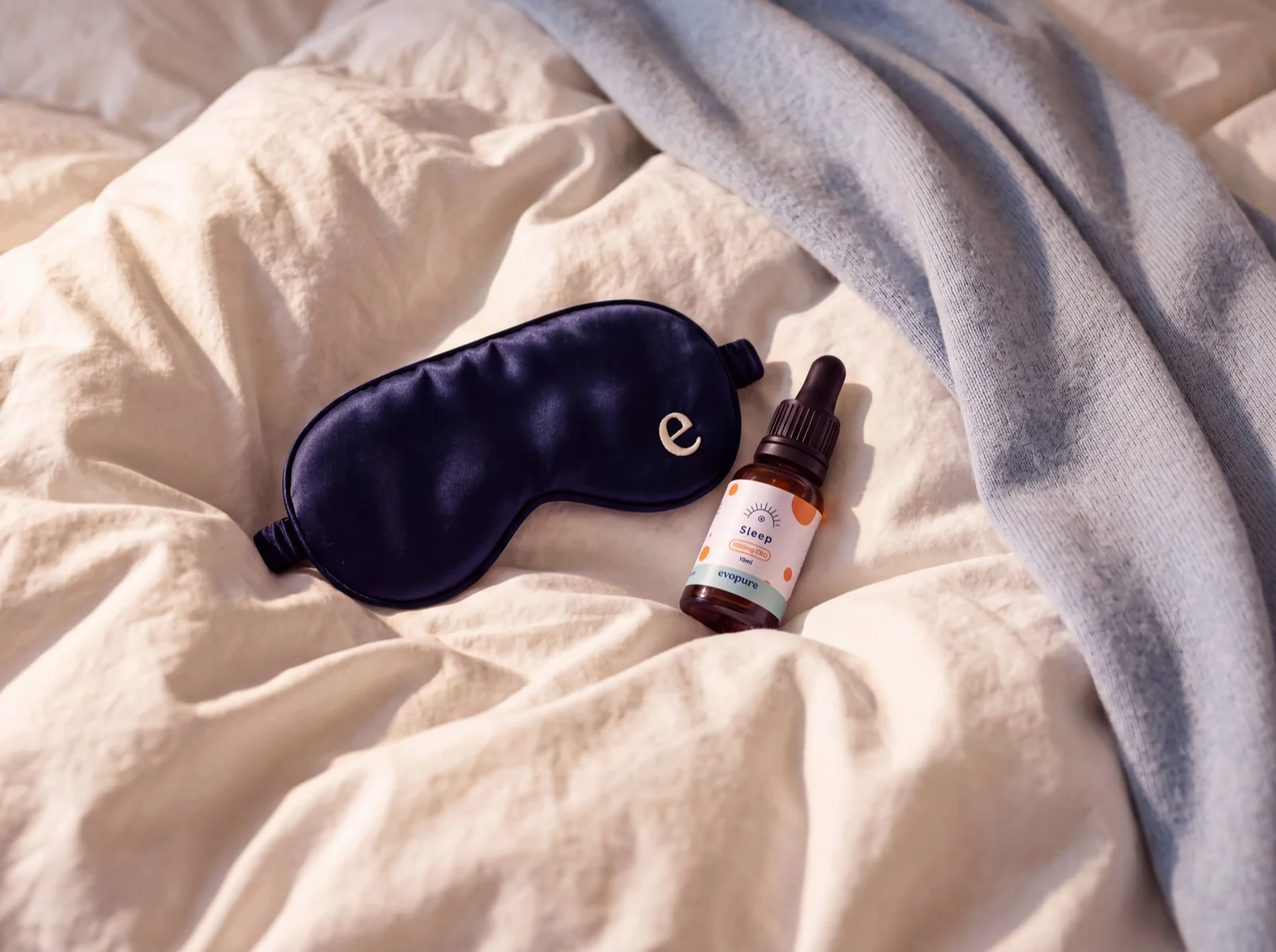 Evopure Sleep CBD oil bottle and box on a pale sage wall with leaf shadows