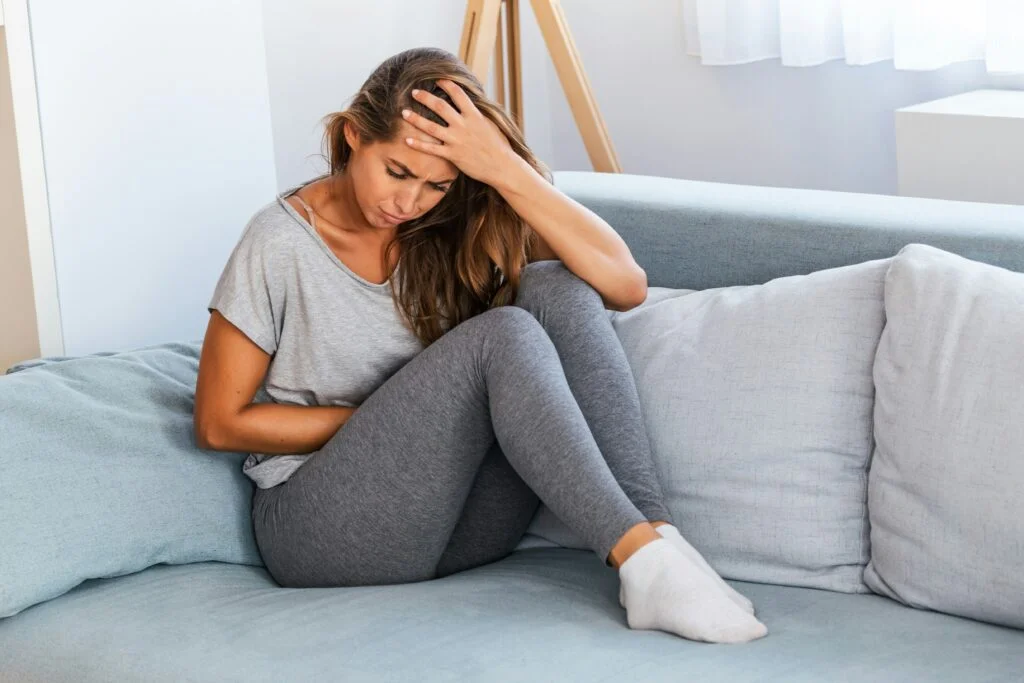 A woman holding her head on the sofa