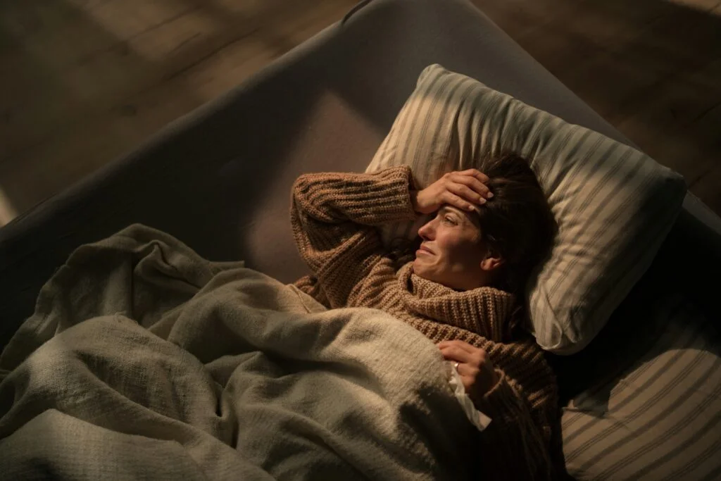 A woman lying awake in bed at night, looking anxious