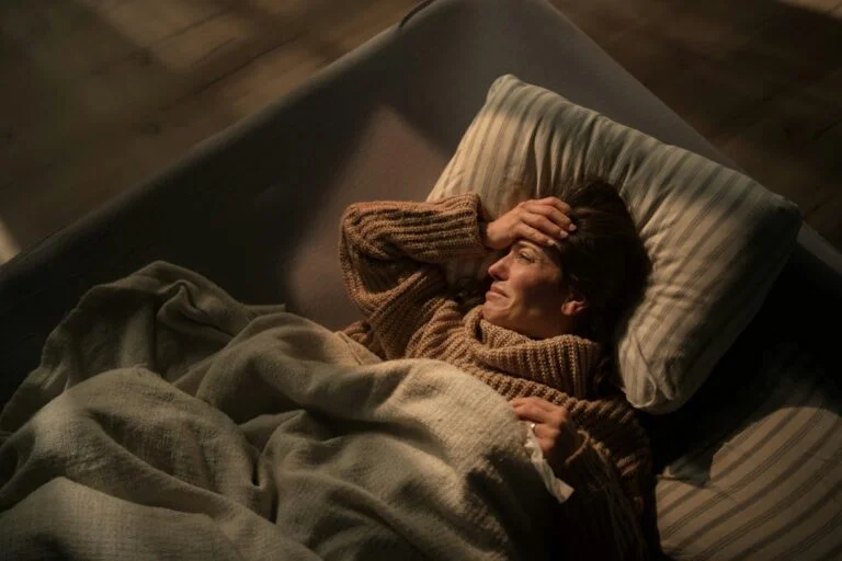 A woman lying awake in bed at night, looking anxious