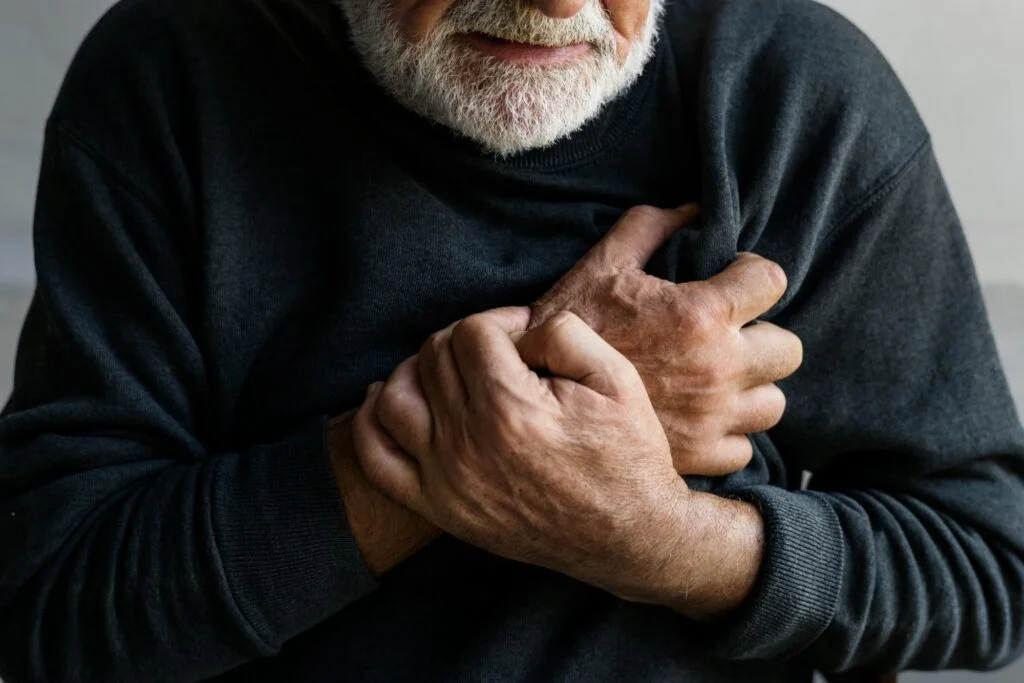 An older man holding his hands to his chest
