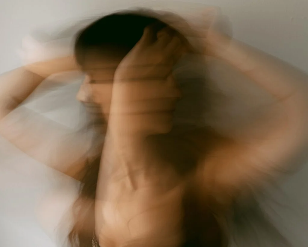 A blurred image of a woman holding her head, feeling dizzy