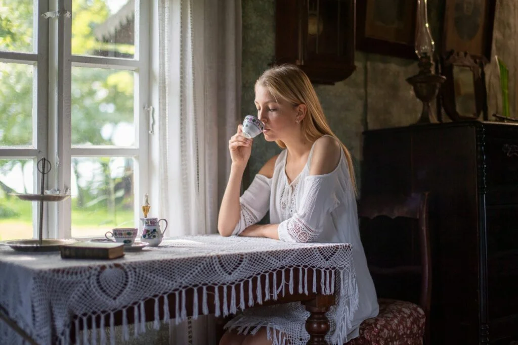 Woman sipping a hot drink by a sunny window