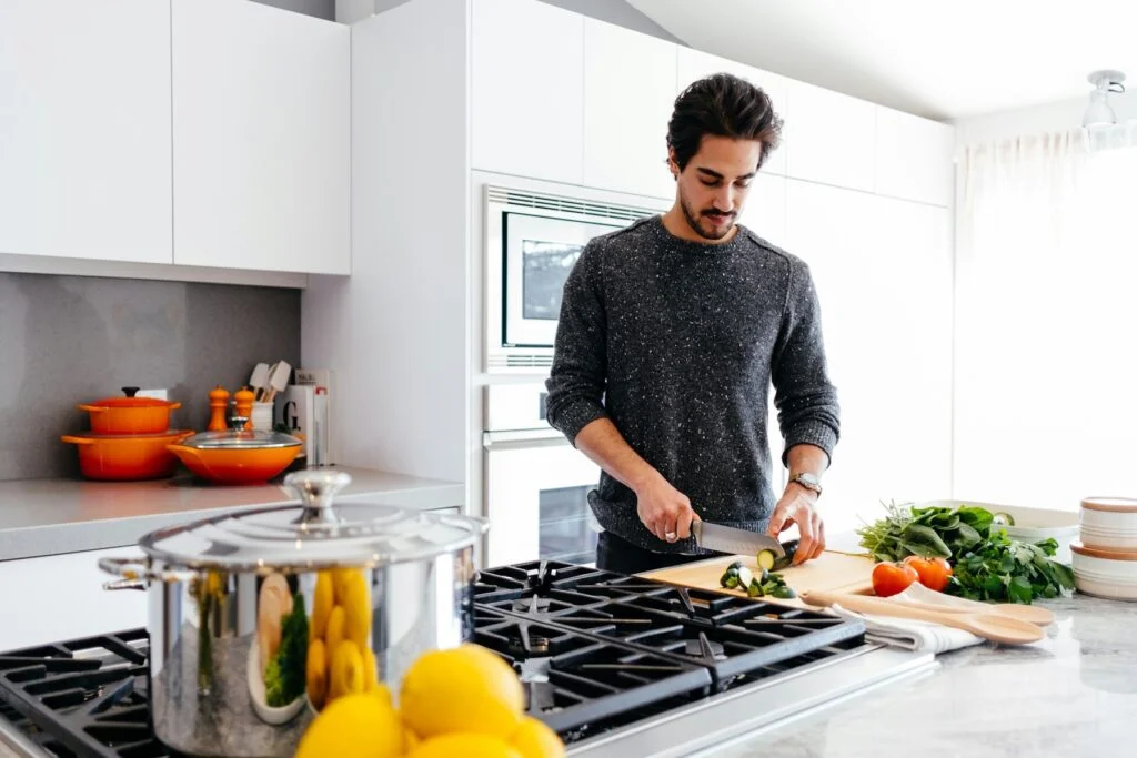 A man chopping fresh vegetables in a bright home kitchen
