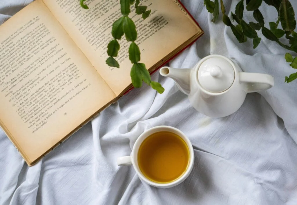 Cup of herbal tea and an open book on a bed at bedtime