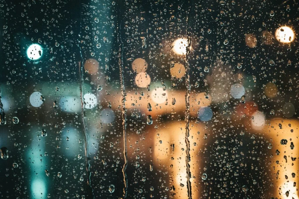 Raindrops on a window at night with soft blurred city lights