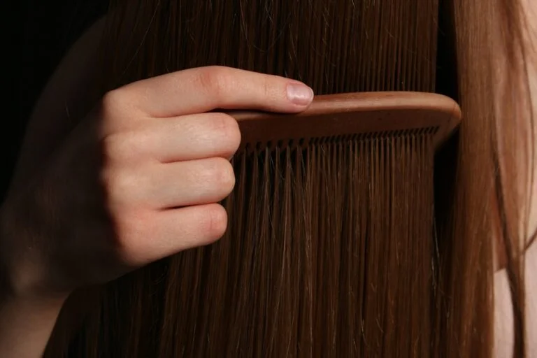 Hand brushing long brown hair with a wooden brush