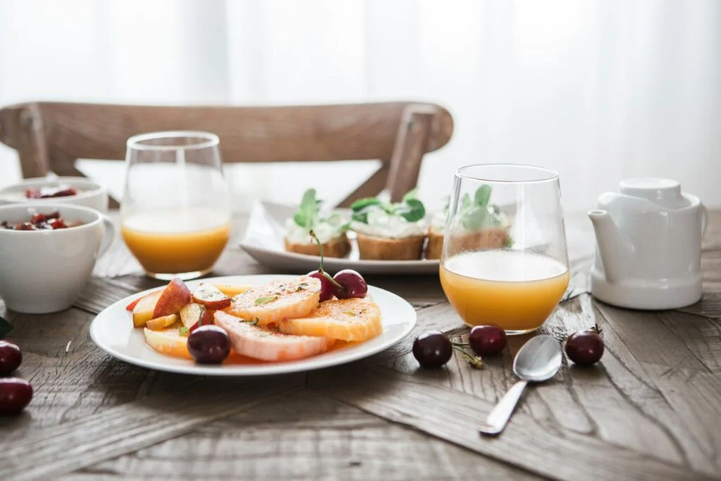 Breakfast table with fruit and orange juice in morning light