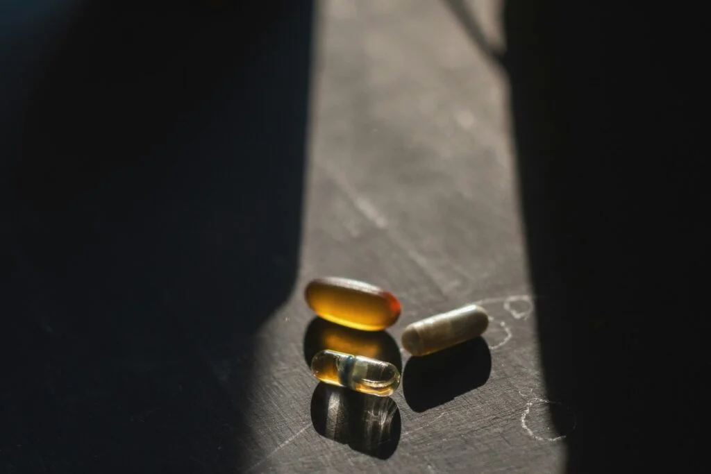 Supplement capsules in a strip of window light on a dark table