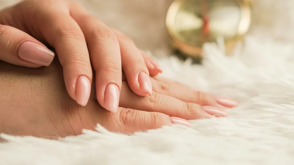 Hands with short natural nails resting on a soft white rug