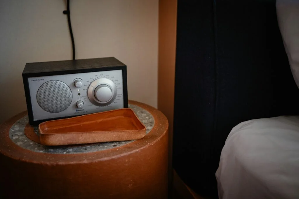 Small radio on a bedside table next to a bed