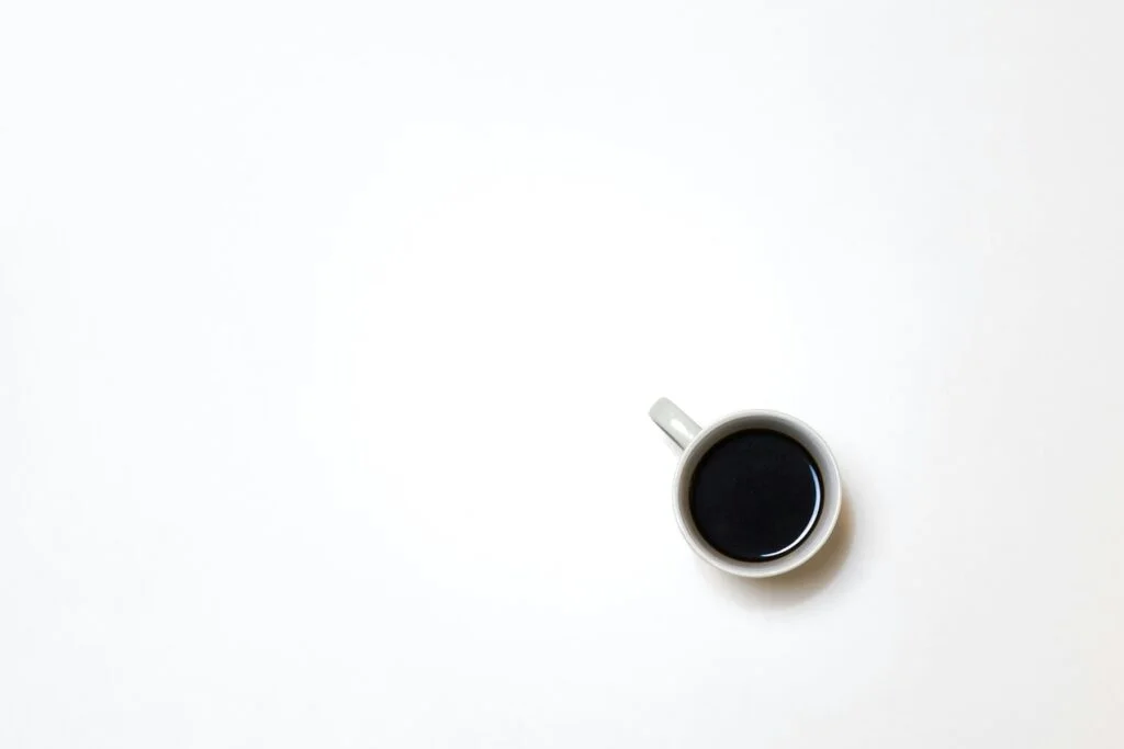 A single cup of black coffee on a plain white surface