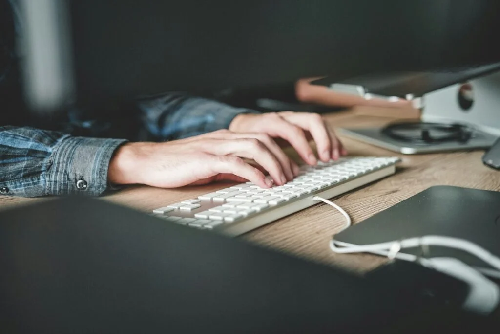 Hands typing on a computer keyboard at a desk