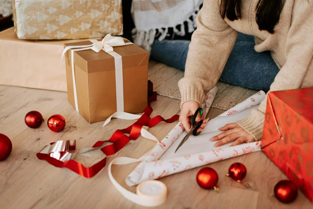 A woman sitting on the floor wrapping Christmas presents