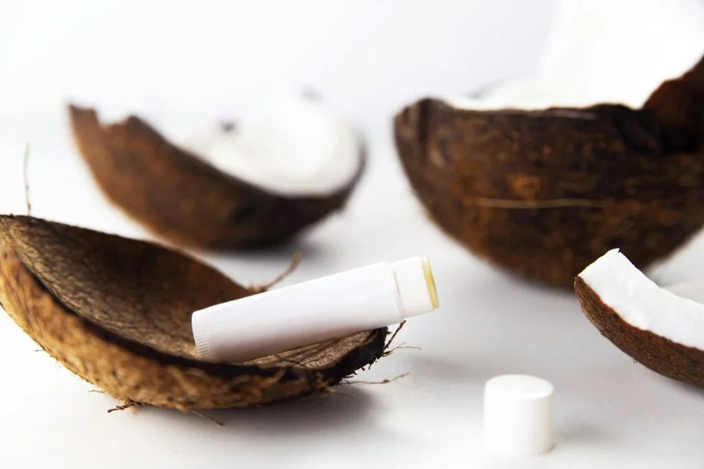 A plain lip balm tube resting on halved coconut shells