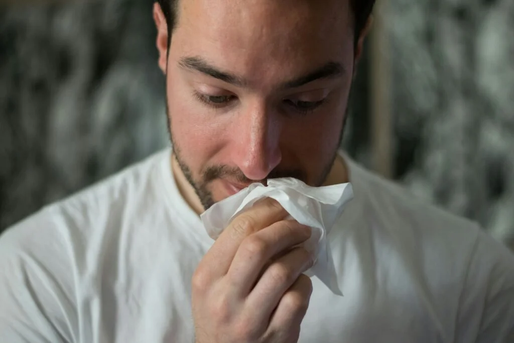 Man with a cold blowing his nose into a tissue