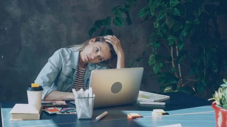 Stressed woman resting her head on her hand at a laptop