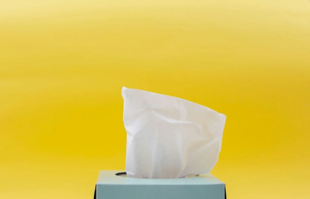 A box of tissues against a bright yellow background