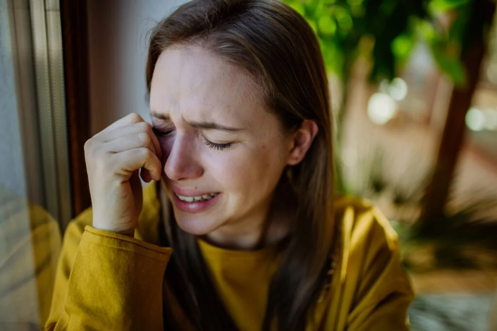 A young woman crying and wiping a tear from her eye