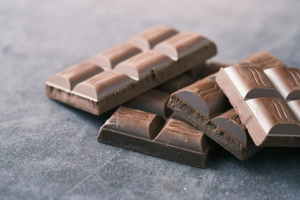 Pieces of a dark chocolate bar stacked on a grey surface