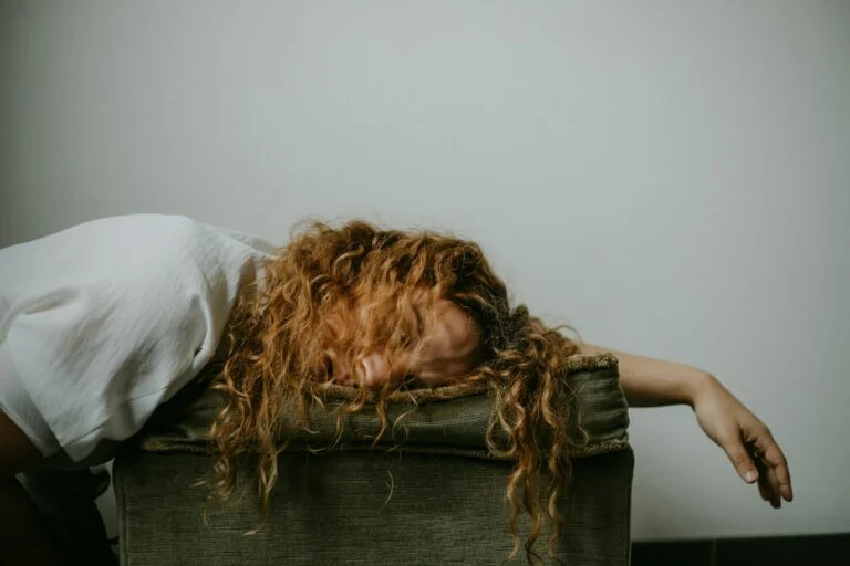 An exhausted woman resting her head on a footstool