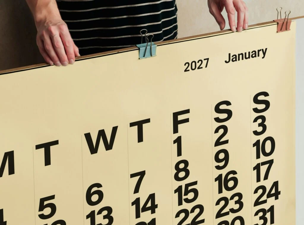 Person holding a large wall calendar for January 2027