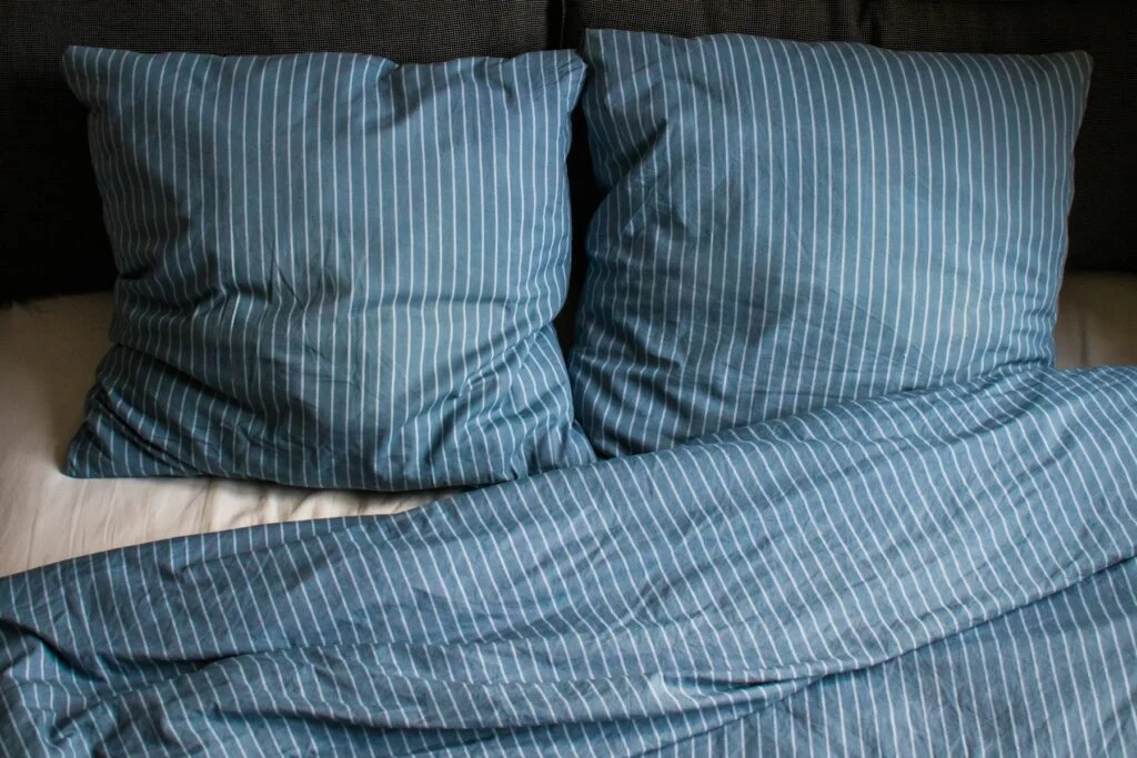 Striped blue pillows and duvet on an unmade bed