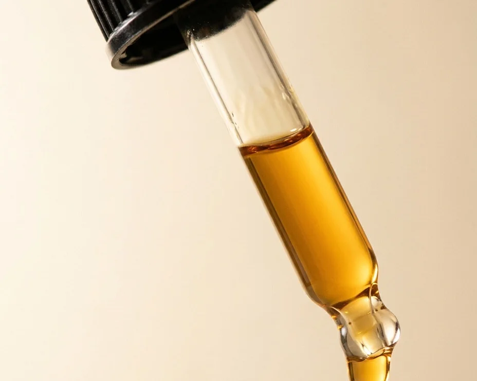 Close-up of a CBD oil dropper with a drop forming at the tip