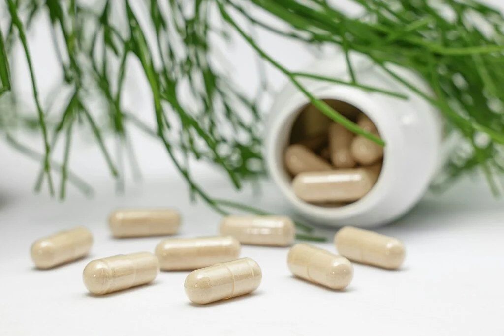 Supplement capsules spilling from a white bottle