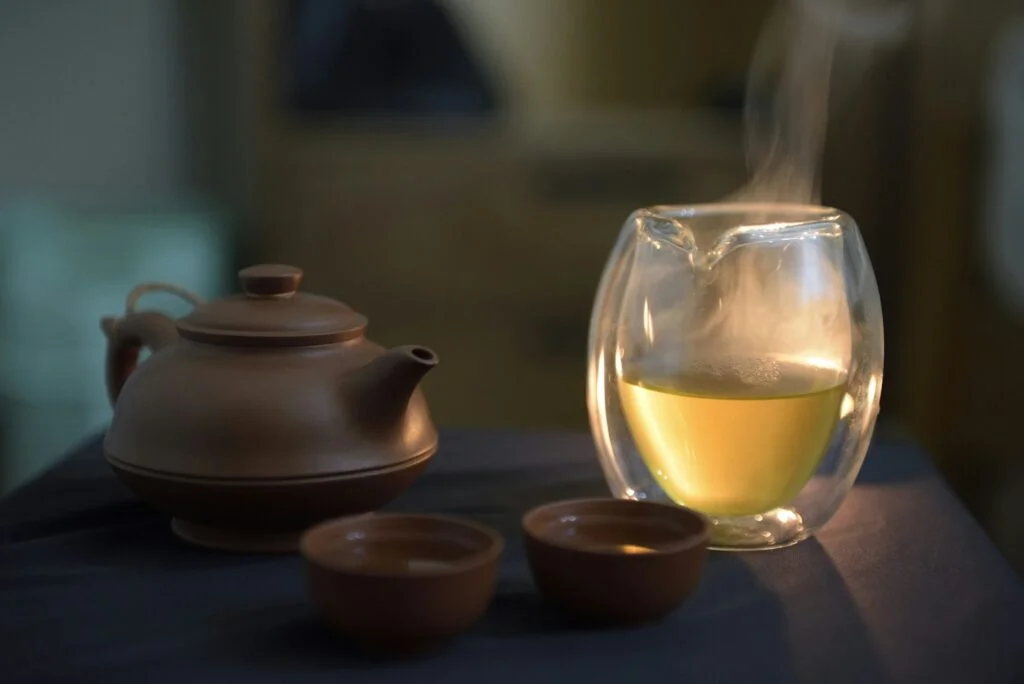 Steaming glass of a warm evening drink beside a teapot
