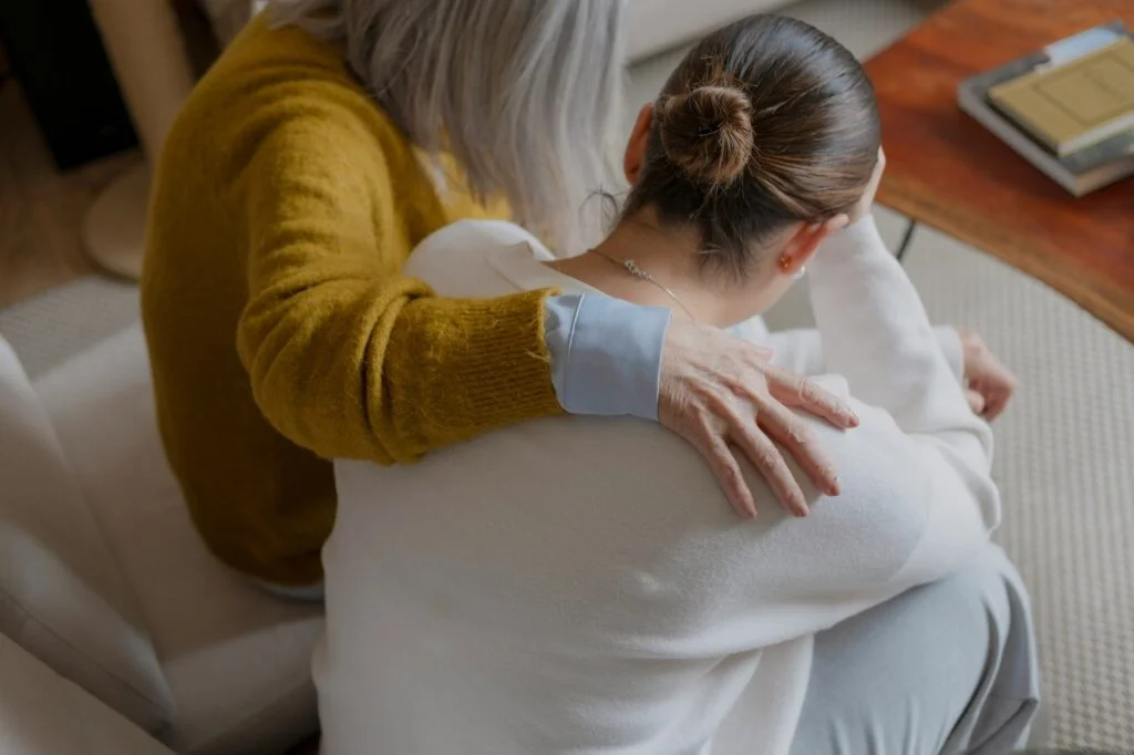 An older woman comforting a younger woman with an arm around her shoulders