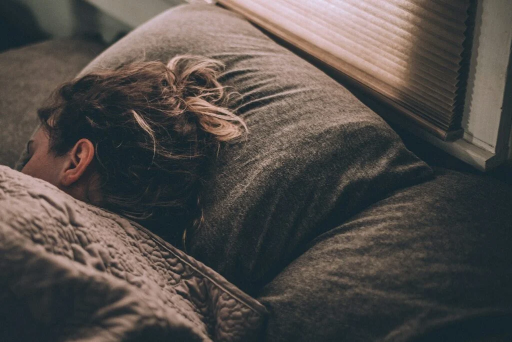 Person lying in bed in a dim bedroom at night
