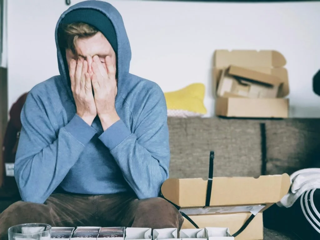 Man in a hoodie rubbing his tired eyes
