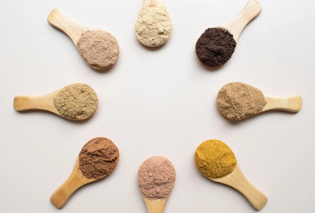 Herbal powders including ashwagandha root on wooden spoons