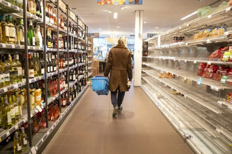 Shopper walking down a supermarket aisle with a basket
