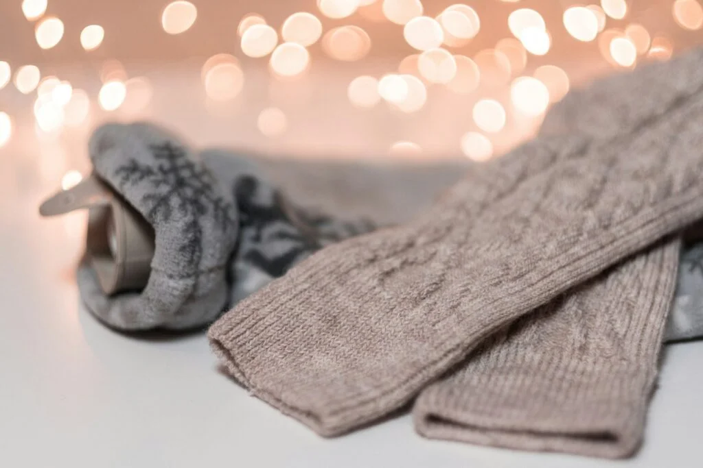 Cosy knitted winter covers and socks in front of soft fairy lights