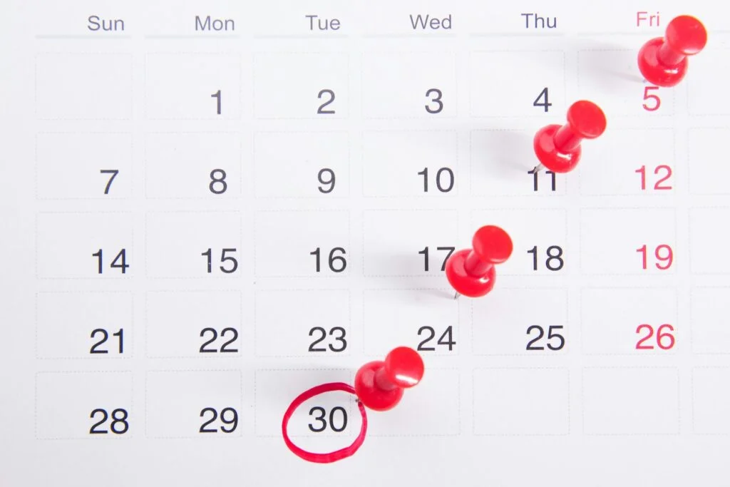 Calendar with red pins marking dates across the month