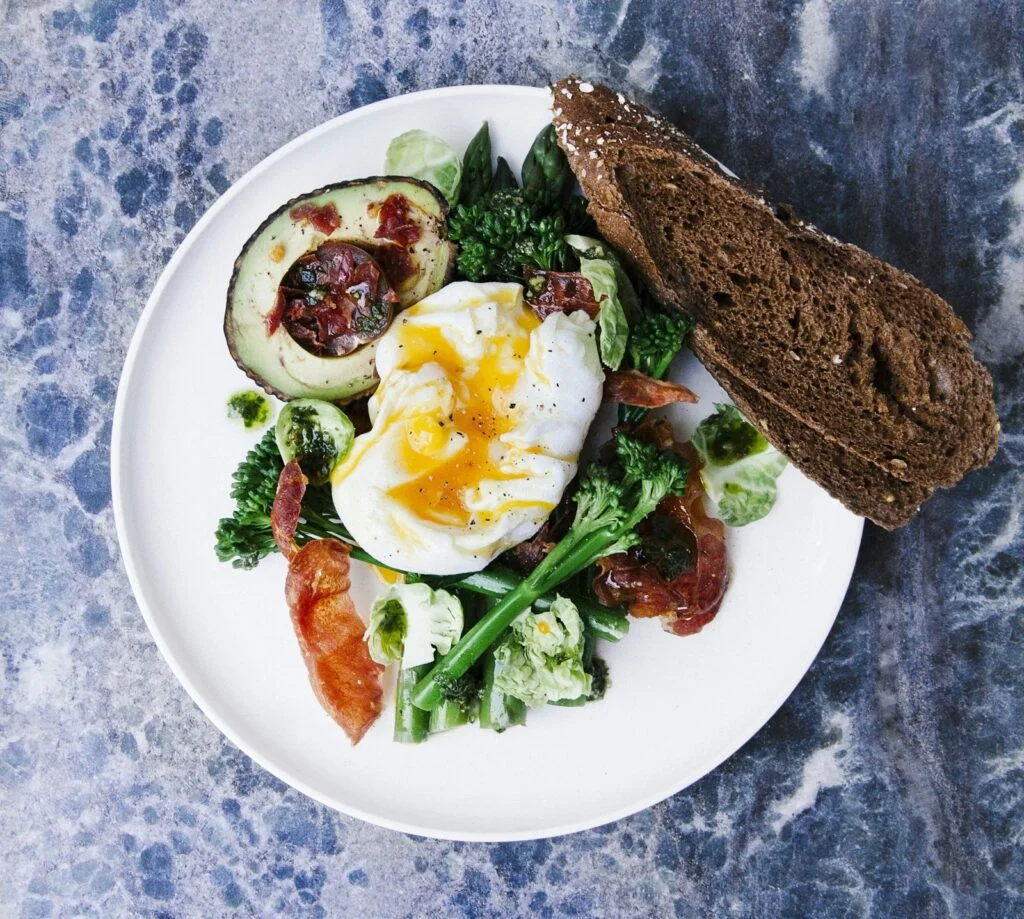 Plate of poached egg, dark greens, broccoli and wholegrain bread