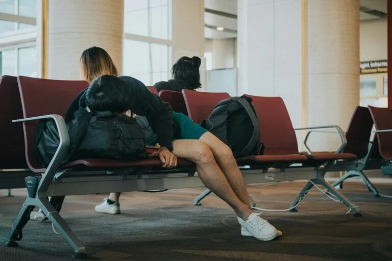 Tired travellers asleep across seats in an airport departure lounge