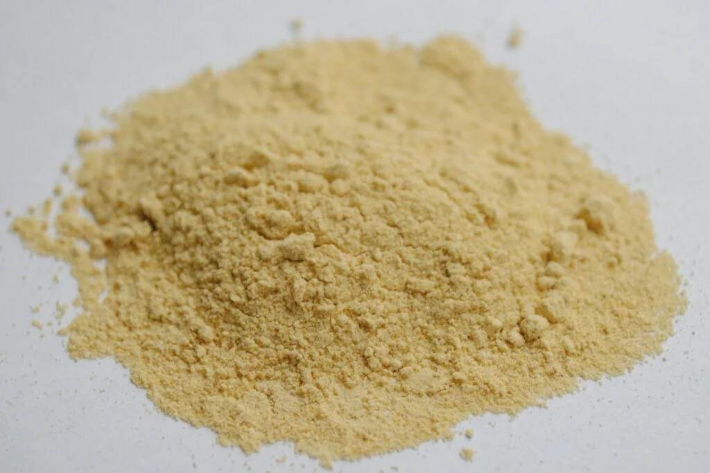Brown herbal root powder on a white surface