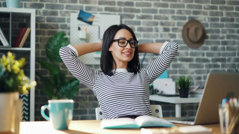 A woman at her desk stretching with her hands behind her head