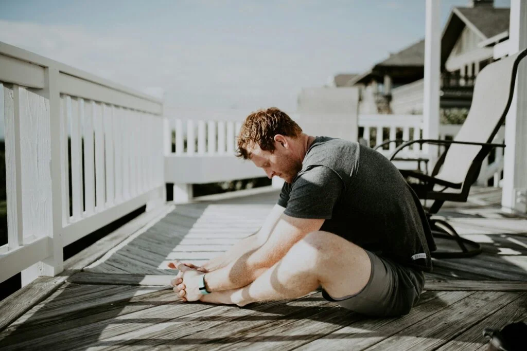 Man stretching his legs on a sunny porch after exercise